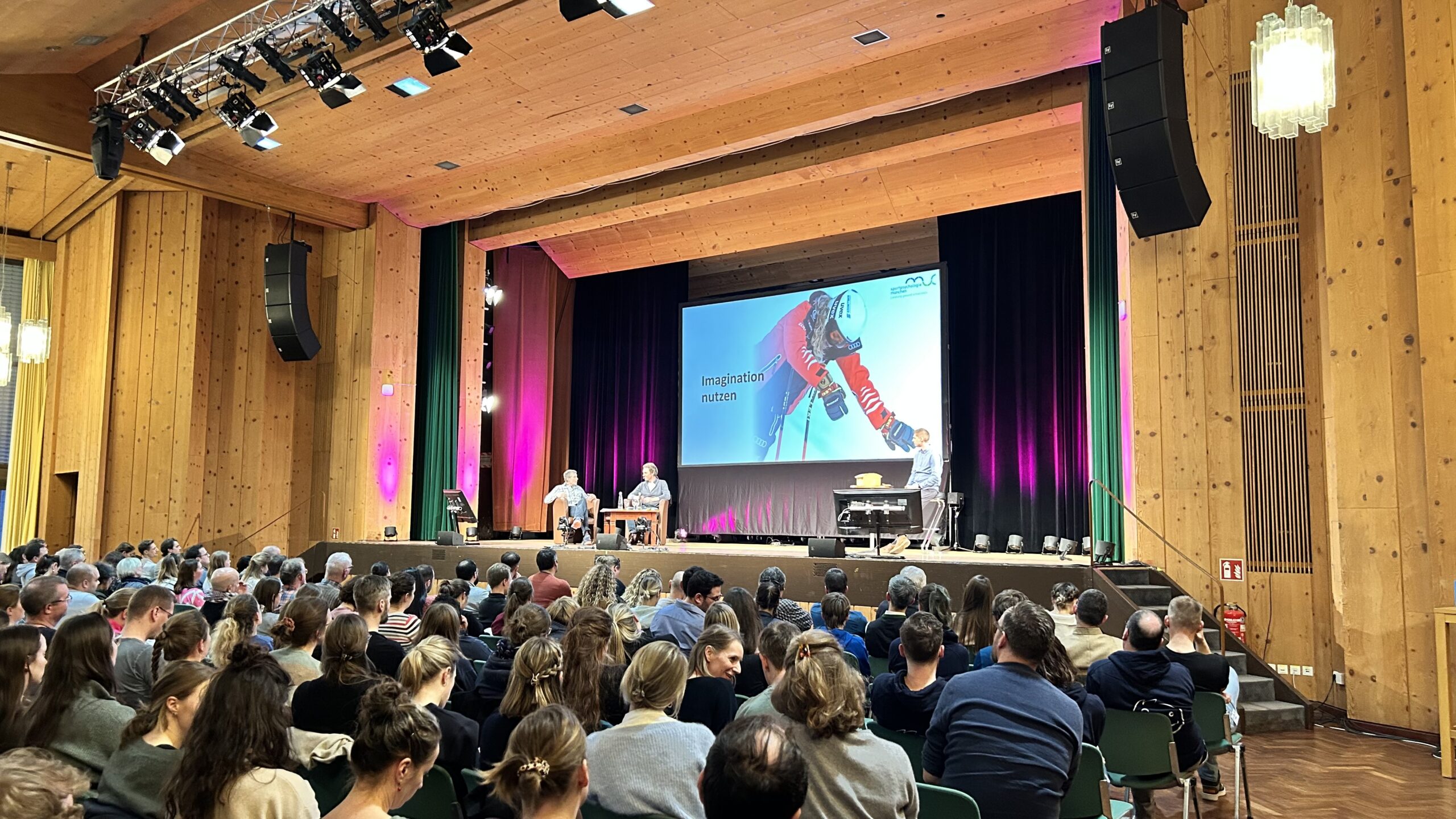 Referenten auf einer großen Bühne mit Multimedialandwand in Garmisch-Partenkirchen.
