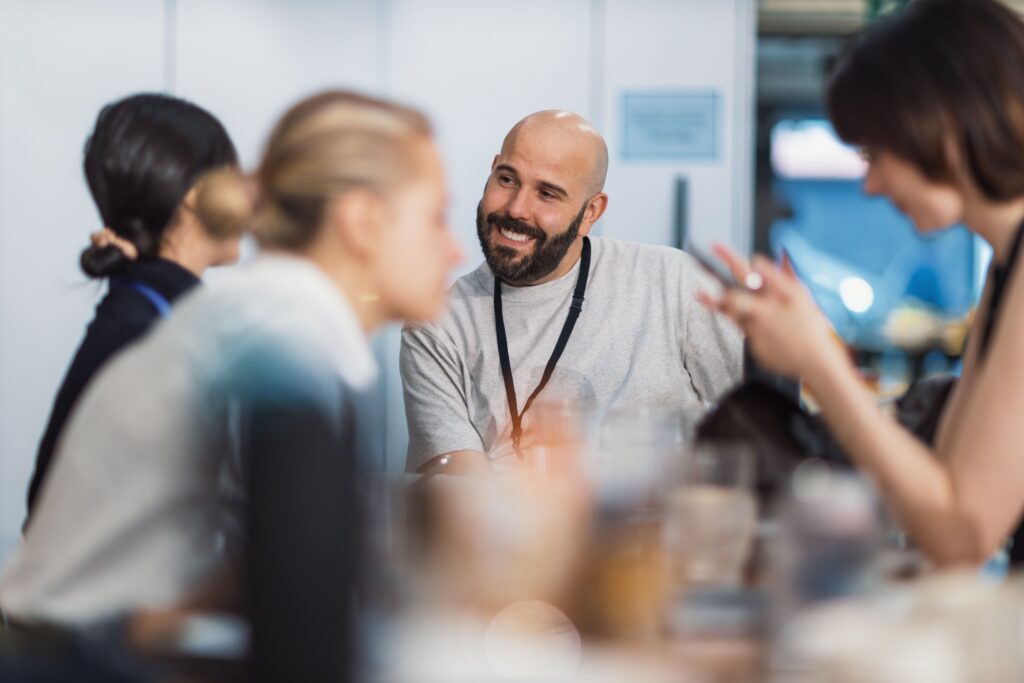 Ein lächelnder Mann im professionellen Networking-Gespräch auf einer medizinischen Industrieausstellung.
